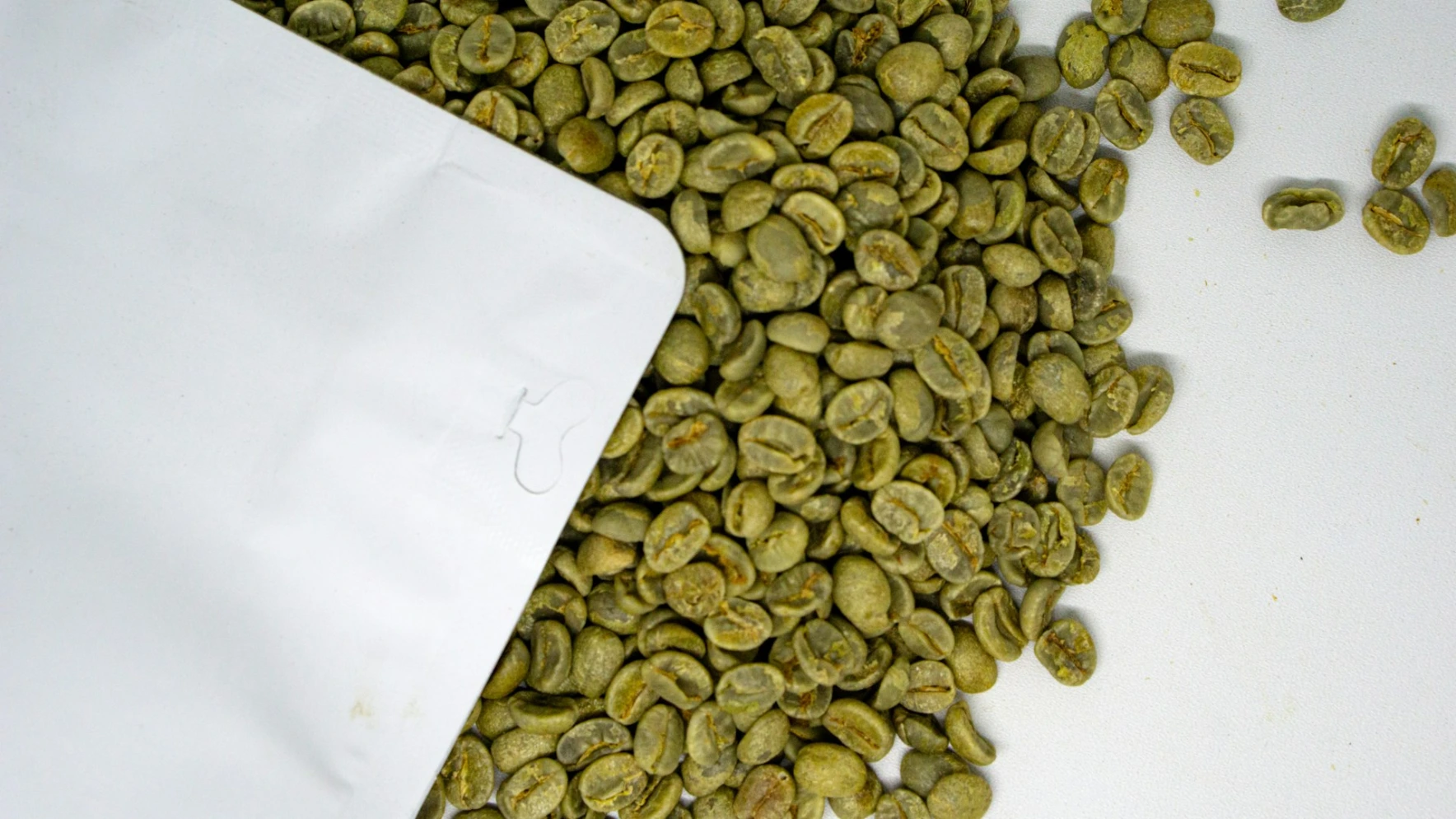 green coffee for extract a pile of green coffee beans next to a white envelope