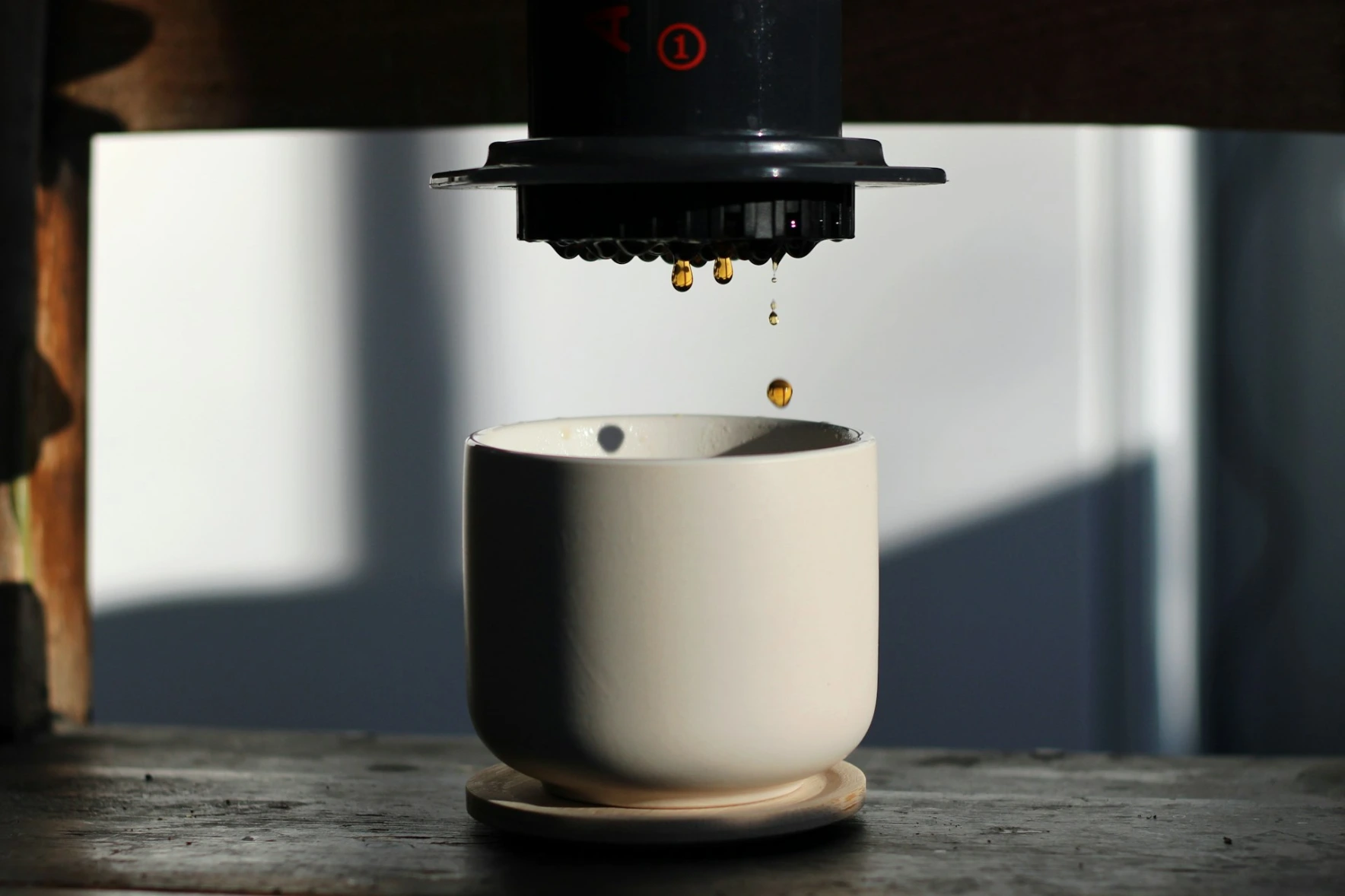 AeroPress is now brewing coffee a coffee cup being poured into a white cup below an AeroPress